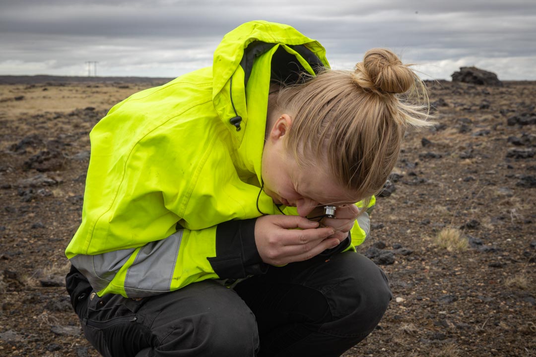 Ung kona skoðar gróður í stækkunargleri